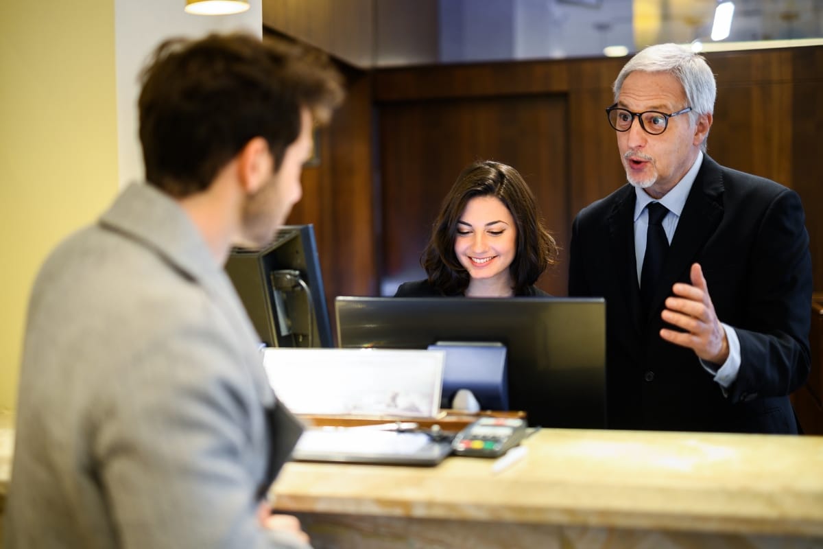 Hotel staff assisting guest at reception desk