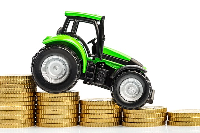 farmers in agriculture have to reckon with rising costs. higher preies in fodder, fertilizer and plants. tractor with coins
