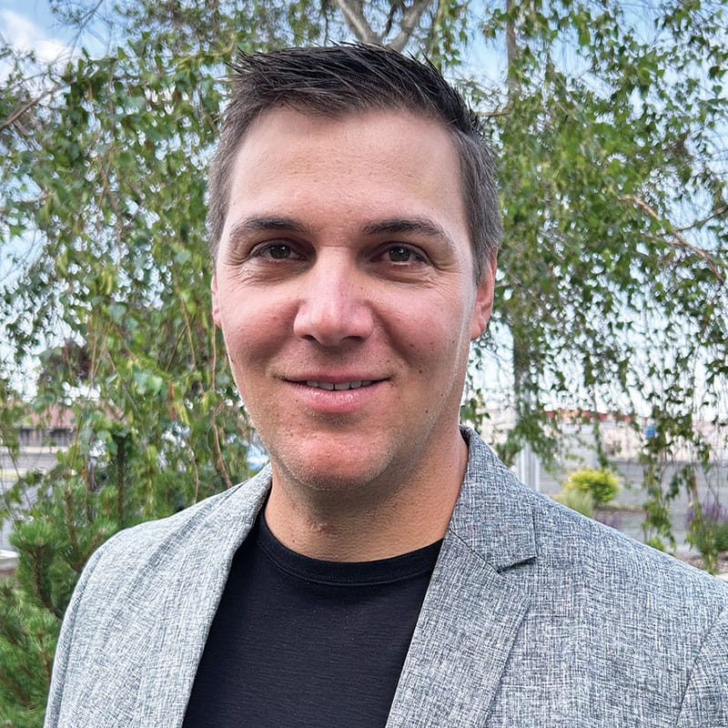 Man in gray blazer smiling outdoors