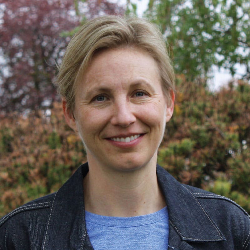 Smiling woman outdoors with trees in background