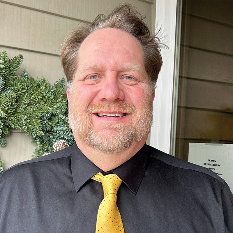 Smiling man in black shirt and yellow tie