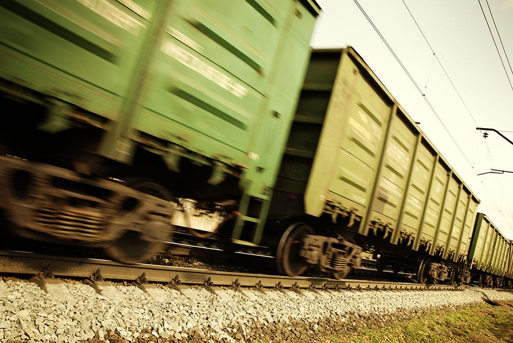 Blurred green freight train speeding along railroad tracks